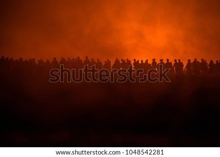 Silhouettes of a crowd standing at field behind the blurred foggy background. Selective focus. Revolution, people protest against government, man fighting for rights
