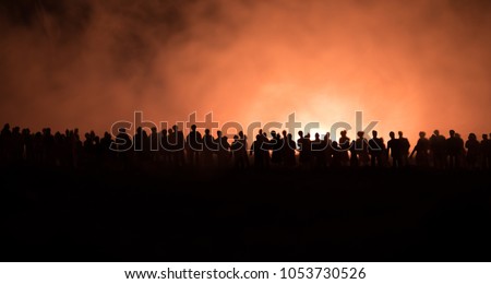 Silhouettes of a crowd standing at field behind the blurred foggy background. Selective focus. Revolution, people protest against government, man fighting for rights