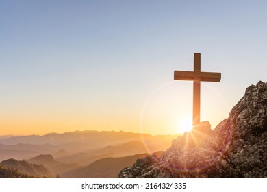 Silhouettes of crucifix symbol on top mountain with bright sunbeam on the colorful sky background - Shutterstock ID 2164324335