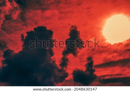 Silhouettes of dark whimsical clouds of different sizes against the background of a crimson sunset. Selective focus.