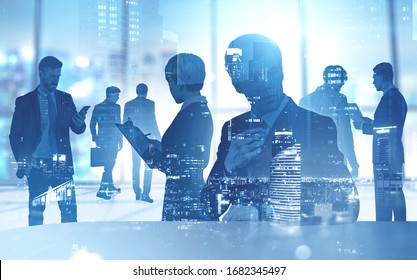 Silhouettes Of Diverse Business People Working Together In Blurry Office With Double Exposure Of Night Cityscape. Concept Of Partnership And Teamwork. Toned Image