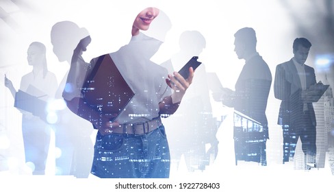 Silhouettes Of Diverse Business People Working Together, Double Exposure Of City Night Skyscrapers, Office Buildings Hologram. Concept Of Internet Connection And Teamwork. Toned Image