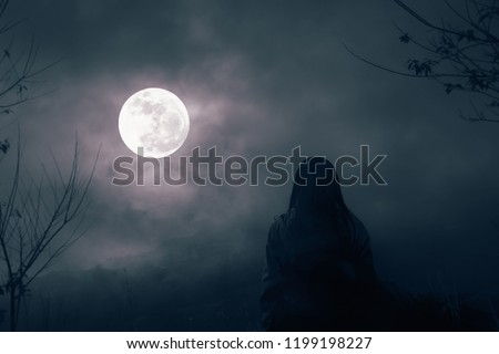 Silhouettes of dry trees against night sky with clouds and Woman stands to watch the full moon in the night alone,nature background
