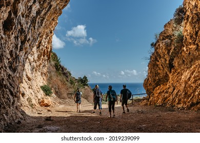 Silhouettes of family on active holiday back view.Group of two seniors and two adults trekking in rocky mountains,Sicily,Italy.Happy multi-generation family walking along coast.Enjoying time together