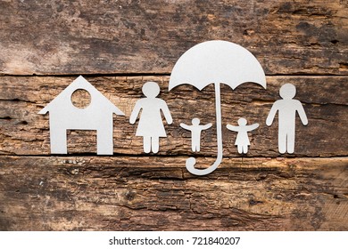 silhouettes of a family of paper under umbrellas near the house - the concept of protection and insurance - Powered by Shutterstock