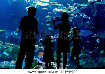 Silhouettes of family with two kids in oceanarium 