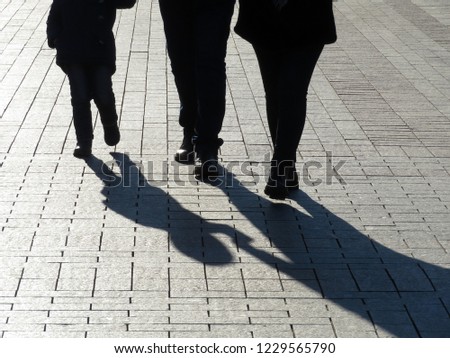 Silhouettes of family walking down the street. Parents holding the child hand, concept for kid adoption, shadows of people