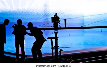 Silhouettes Of Film Crew In Front Of  Blue Lighted Stage. Selective Focus. 