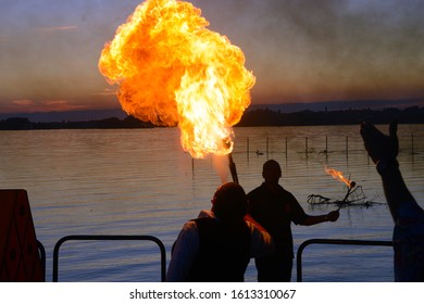 silhouettes of fire eaters at lake during sunset - Powered by Shutterstock