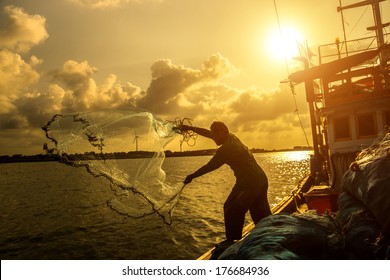 Silhouettes fisherman casting on a crab boat.