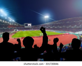 Silhouettes of football fans cheering against large football stadium with lights, sport concept - Shutterstock ID 331720046