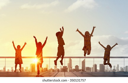 Silhouetten von Gruppen von Kindern, die fröhlich hoch auf Sonnenaufgang springen