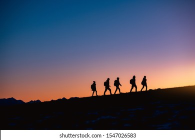 Silhouettes of group of hikers going uphill at sunset mountain - Powered by Shutterstock