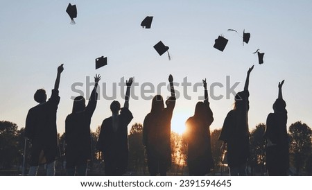 Silhouettes of Happy college graduates tossing their caps up at sunset.