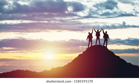 Silhouettes Of Happy Three People On Top Of A Mountain. Success And Achievements, Business, Work In A Team, Cooperation.