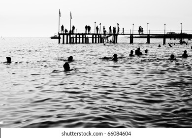Silhouettes of having a rest people. It is black a white photo of a sea pier and having a rest people.