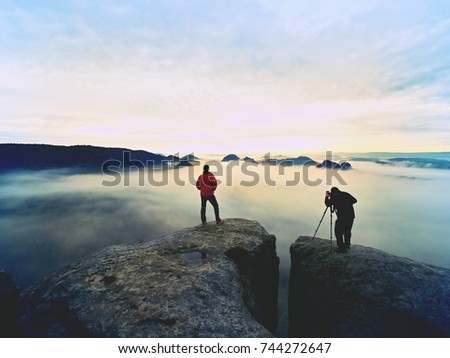 Silhouettes of man photographers. Men on mountain. Peak  with two men taking photos in autumn morning sunrise