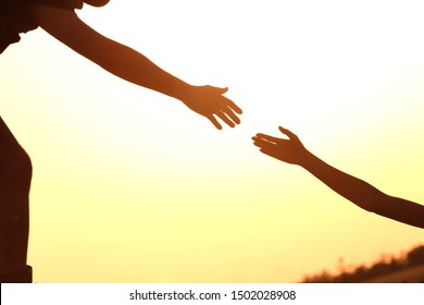 Silhouettes Of Man And Woman Helping Each Other To Climb On Hill Against Sunset, Closeup