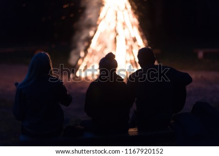 silhouettes of men and women on a fire background. Parking tourists. Playing guitar. Songs around the campfire. blurred picture
