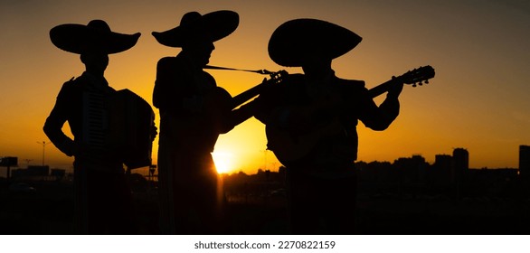Silhouettes of a mexican musicians mariachi band on a background of city panorama.