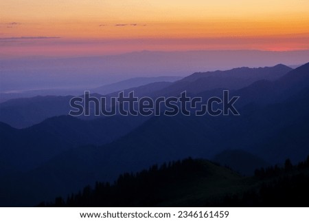 Silhouettes of mountain ranges in the morning haze. Blue hour                               