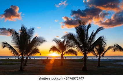 Silhouettes of palm trees and people on the beach of Flic en Flac on the dream island of Mauritius (Indian Ocean). Idyllic scene with a colorful sky at sunset. Popular holiday  honeymoon destination - Powered by Shutterstock