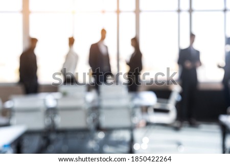 Silhouettes of people against the window. A team of young businessmen working and communicating together in an office. Corporate businessteam and manager in a meeting. Blured image.