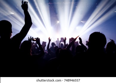 Silhouettes Of People In A Bright In The Pop Rock Concert In Front Of The Stage. Hands With Pacifism Signs On Paper. No War Signs On Concert