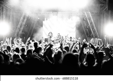 Silhouettes of people at a concert in front of the scene in bright light. Black and White