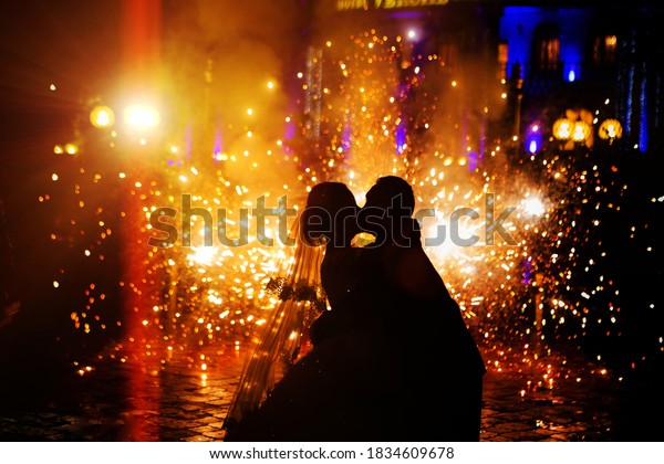 silhouettes of people kissing against the background of fireworks and fireworks
