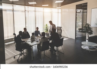 Silhouettes Of People Sitting At The Table. A Team Of Young Businessmen Working And Communicating Together In An Office. Corporate Businessteam And Manager In A Meeting