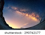 Silhouettes of the people standing together holding hands against the Milky Way in the mountains. 