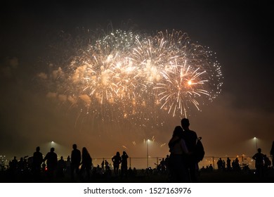 silhouettes of people watching fireworks in the background of bright yellow flashes in the night sky - Powered by Shutterstock