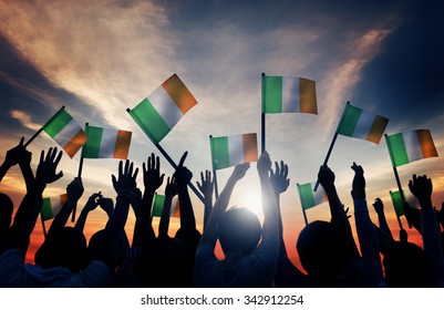 Silhouettes Of People Waving The Flag Of Ireland