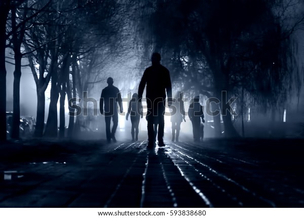 Silhouettes of people zombie walk at night\
in the city in the moonlight in the soft blurred focus on a dark\
blue background. Artistic image of a zombie\
people.