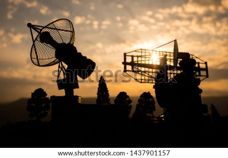 Silhouettes of satellite dishes or radio antennas against night sky. Space observatory or Air defence radar over dramatic sunset sky. Creative artwork decoration. Selective focus