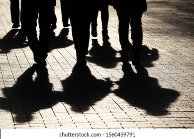 Silhouettes and shadows of people on the city street. Crowd walking down on sidewalk, concept of strangers, crime, society, gang or population - Shutterstock ID 1560459791