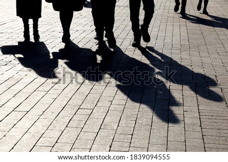 Silhouettes and shadows of people on the city street. Crowd walking down on sidewalk, concept of crime, society or population