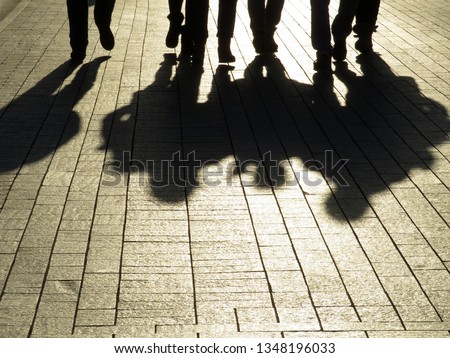 Silhouettes and shadows of people on the street. Crowd walking down on sidewalk, concept of strangers, crime, mafia, society, street gang