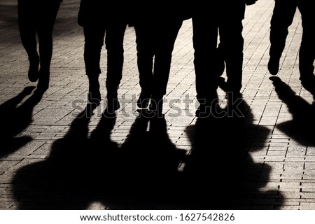 Silhouettes and shadows of people on the street. Crowd walking down on sidewalk, concept of strangers, crime, society, epidemic, population