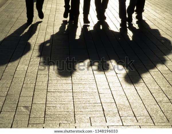 Silhouettes and shadows of people on the street.\
Crowd walking down on sidewalk, concept of strangers, crime, mafia,\
society, street\
gang