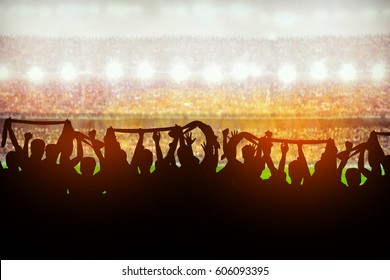 Silhouettes of soccer or rugby supporters in the stadium during match - Powered by Shutterstock