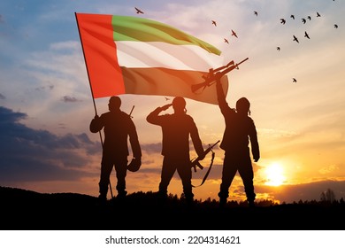 Silhouettes Of Soldiers With The Flag Of UAE Against Sunset Or Sunrise. Concept Of National Holidays. Commemoration Day.