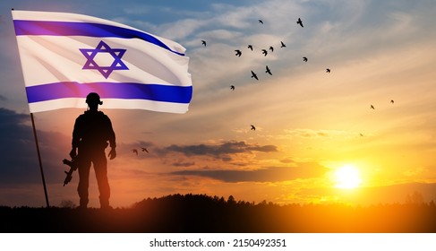 Silhouettes of soldiers with Israel flag and flying birds against the sunrise in the desert.