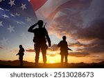 Silhouettes of a soldiers with USA flag against the sunset. Veterans Day. Honoring All Who Served