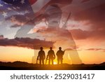 Silhouettes of a soldiers with USA flag against the sunset. Veterans Day, Memorial Day concept