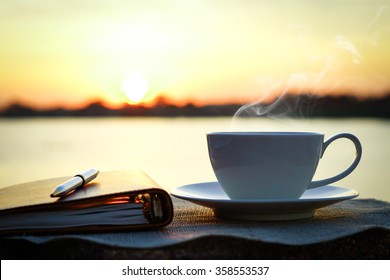 Silhouettes of sunrise morning coffee with a note and a pen - Shutterstock ID 358553537