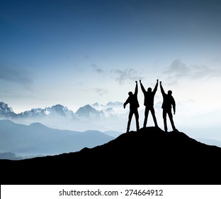 Silhouettes of team on mountain peak. Sport and active life concept