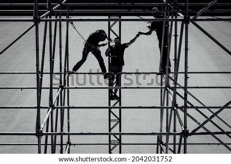 Silhouettes of three men assembling the scaffolding