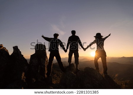  Silhouettes of three people climbing on mountain and helping. Help and assistance concept.